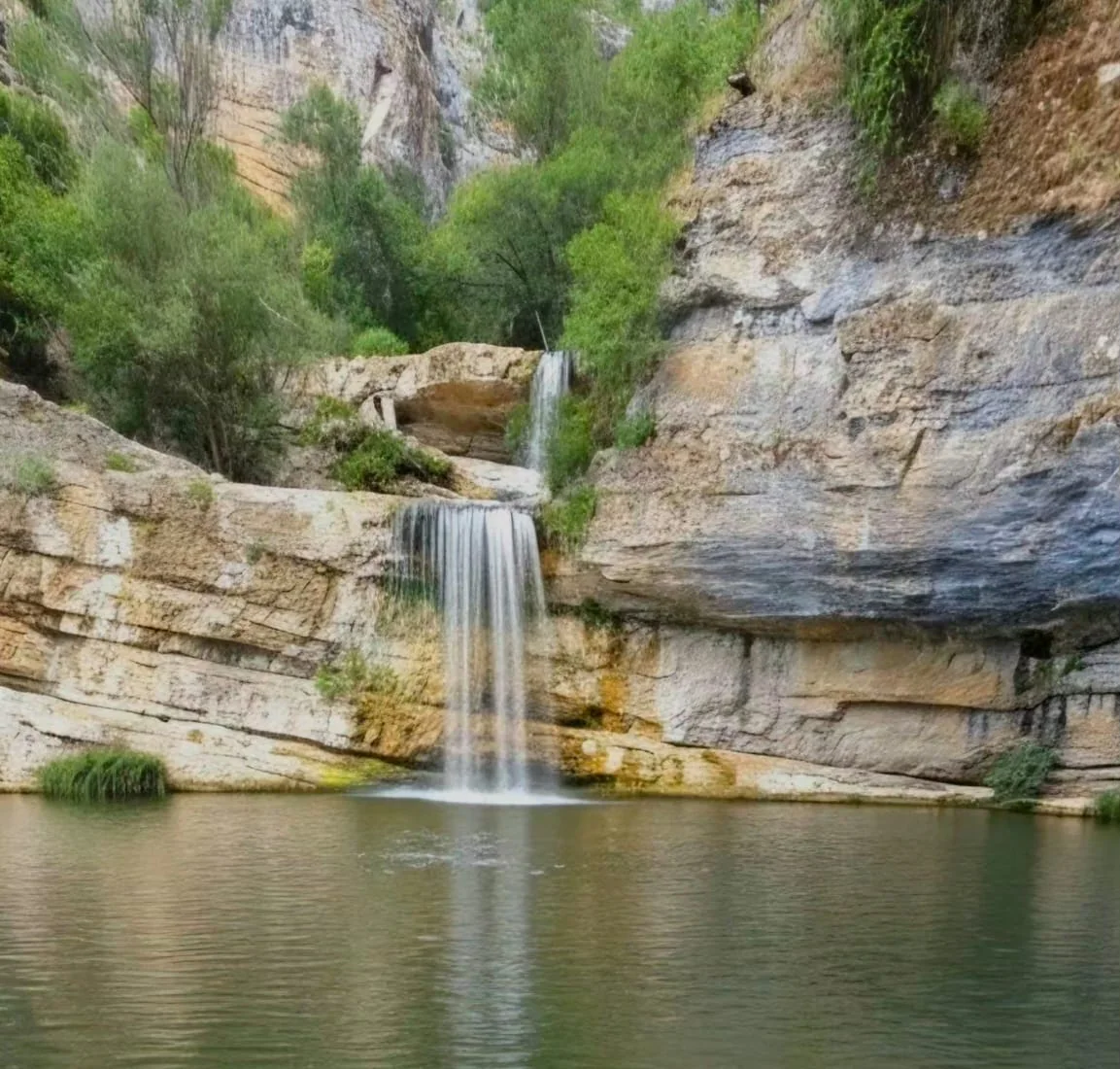 Water cascading through a limestone canyon into a clear pool